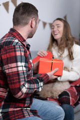 Selective focus of happy couple presenting each other gifts in holiday