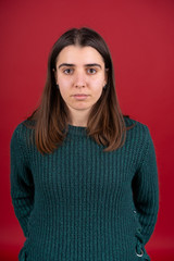 Front view of attractive brunette girl in sweater isolated on red background