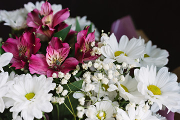A bouquet of white chrysanthemums and pink alstroemeria flowers on a black background