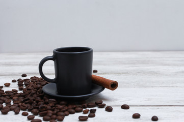 Dark grey cup of coffee, cinnamon and beans on white wooden table. Coffee shop, spice, espresso, side view