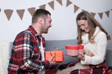 Smiling couple presenting each other gifts in holiday