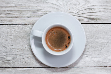 White cup of coffee on white wooden table. Coffee shop, espresso, top view, copy space, template