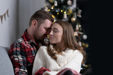 Happy couple sitting near decorated christmas tree