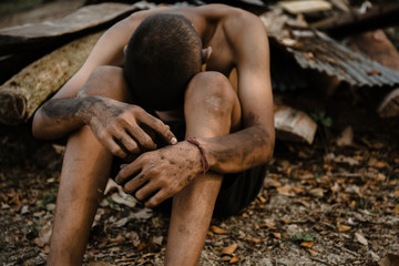 poor child or beggar begging you for help sitting at dirty slum. concept for poverty or hunger...