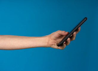 Female hand holding smartphone isolated on blue background
