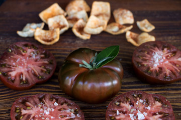 Fototapeta premium Schwarze tomate mit tomatenscheiben und chips aus humus mit tomate