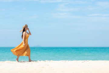 Fototapeta na wymiar Summer Holiday. Lifestyle woman chill with wearing yellow dress fashion summer trips walking chill on the sandy ocean beach. Happy people enjoy and relax vacation. Lifestyle and Travel Concept.