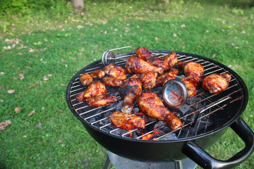 Chicken wings and legs cooking on the grill on sunny day outdoors