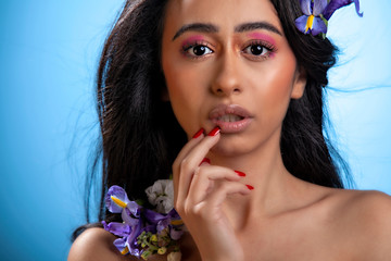 beautiful young Arabic female model in the studio posing with flowers highlighting her healthy skin and long black hair. her elegant eyes and stylish make up are glamorous 