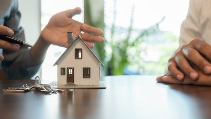 House model with agent and customer discussing for contract to buy, get insurance or loan real...