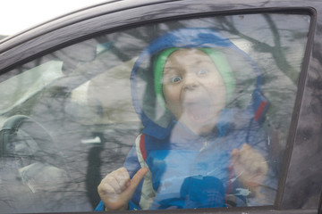 Little boy screams behind a car window