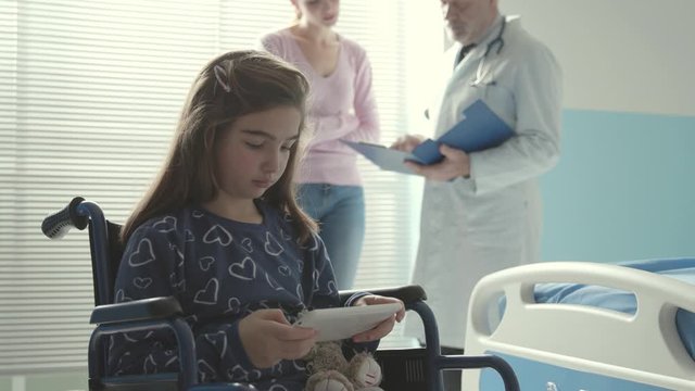 Girl in wheelchair using a digital tablet at the hospital