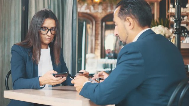 Two businesspeople in deep blue suits are working. Man is working on tablet. Woman is buying in internet with a help of shopping card. Close up. Copy space.