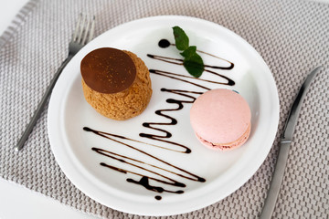 Homemade sweet profiteroles with custard, french biscuits macaroon and cup of coffee on gray napkin . Spring or summer dessert concept. Close up. traditional french desserts
