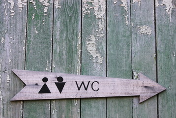 Toilet pointer on the Old shabby wooden planks with cracked color paint. wooden arrow with special...