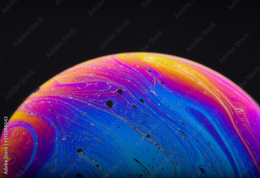 Wall mural close up macro photograph of the psychedelic rainbow of colors mixing and swirling in a soap bubble 
