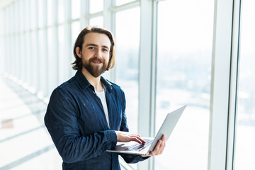 Business man using laptop with panoramic city view outside window background