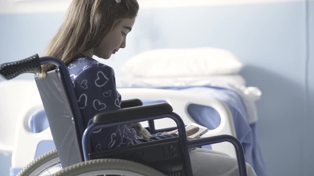 Girl in wheelchair using a digital tablet at the hospital