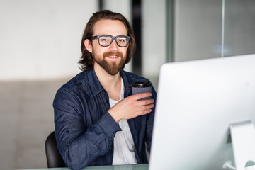 Happy young businessman drinking coffee in office