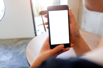 Mockup picture of business man's hands or woman’s hands holding smart phone with white blank screen in modern place.