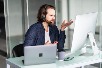 Angry call center operator working at his desk on computer and laptop