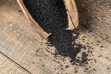 Black cumin seeds on a vintage scoop on a table