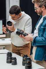 bearded art director holding photo lens near photographer