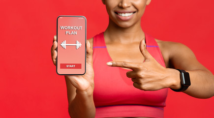 Fitness lady pointing at workout application on phone screen