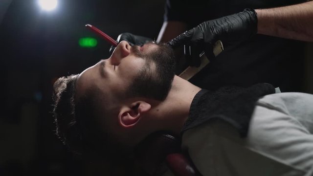 Side view of handsome young guy getting shaved at salon