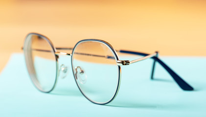 Glasses in a thin metal frame on a colorful background, close-up, selective focus. Thin-rimmed glasses.