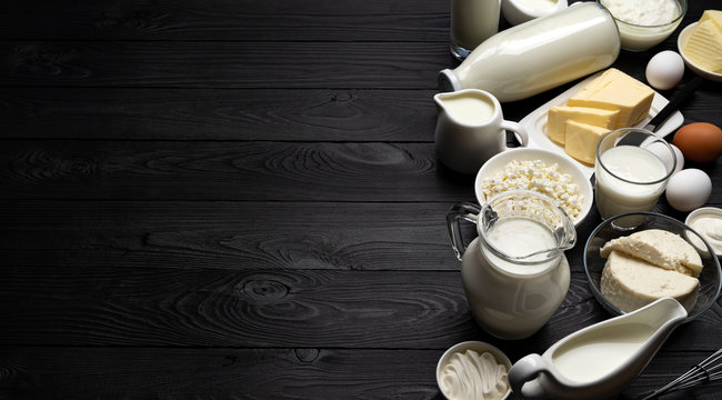 Dairy products on black wooden background, top view