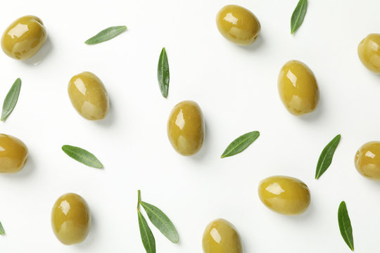 Green olives and leaves on white background, top view