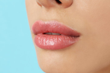 Fototapeta premium Woman with beautiful full lips on light blue background, closeup