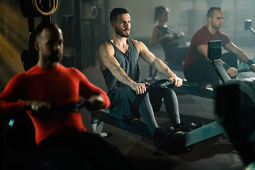 Group of athletes exercising on rowing machines in a gym.