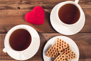two cups of tea with heart-shaped cookies, top view on a rustic background. Valentine's Day