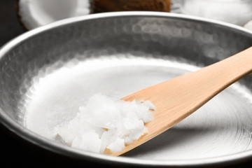 Frying pan with coconut oil and wooden spatula, closeup. Healthy cooking