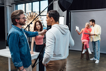 happy art director looking at handsome assistant in photo studio