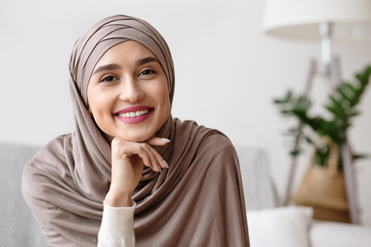 Portrait of smiling muslim girl in hijab resting head on hand