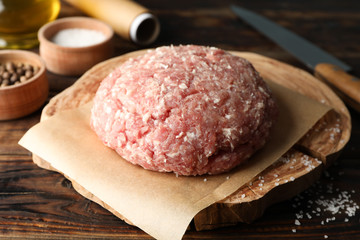 Spices and board with minced meat and knife on wooden background, close up