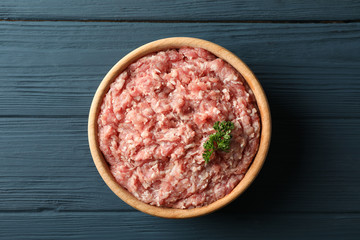 Bowl with minced meat on wooden background, top view