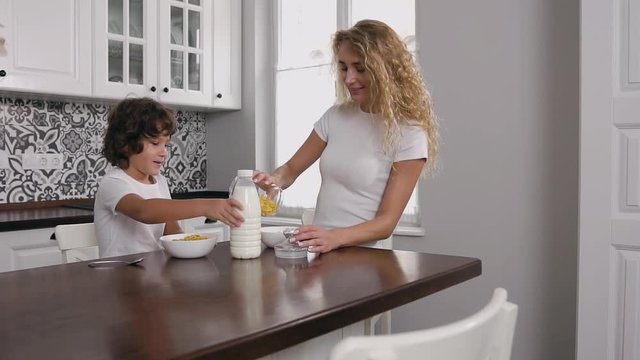 Young woman having breakfast with son at home in modern kitchen