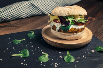 vegan burger with lettuce and tomato on slate tray