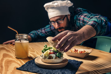 chef finishing up his vegan burger on a wood table