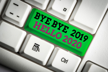 Handwriting text writing Bye Bye 2019 Hello 2020. Conceptual photo Starting new year Motivational message 2019 is over White pc keyboard with empty note paper above white background key copy space © Zofia