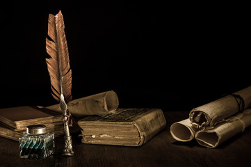 Quill pen and rolled up papyrus sheets  with old books, vintage effect