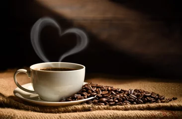 Fotobehang Koffie Kopje koffie met hartvormige rook en koffiebonen op jutezak op oude houten ondergrond