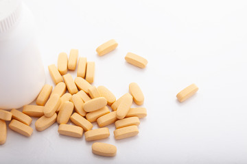 Closeup scattered from white pill bottle orange oval medicine vitamins for pregnancy, pills, drugs isolated on white background. Healthy food diet supplement