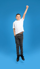 Fototapeta na wymiar Preteen boy jumping on light blue background