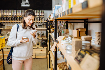 Woman chooses and buys products in zero waste shop.