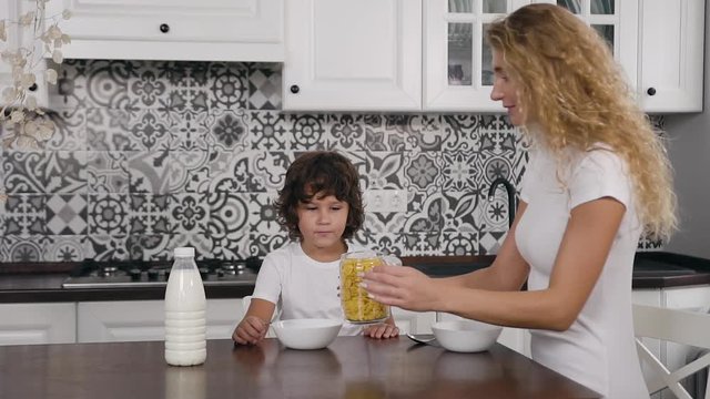 Portrait of a beautiful young woman having breakfast with her five year son in the kitchen